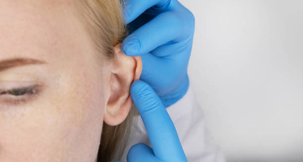 Medical professional examining an infected ear piercing