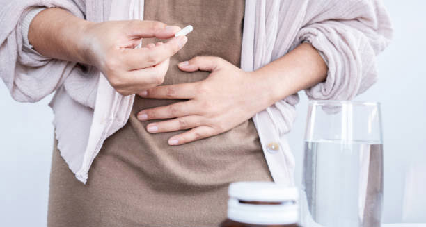 Woman taking medication for inflammatory bowel disease with hand on stomach