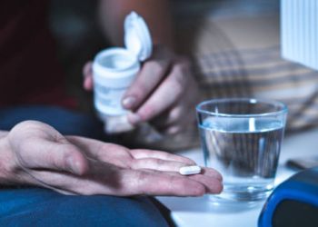 Person taking a sleeping pill with a glass of water at night