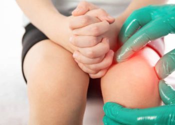 Medical professional examining a child’s inflamed knee for joint hypermobility syndrome treatment