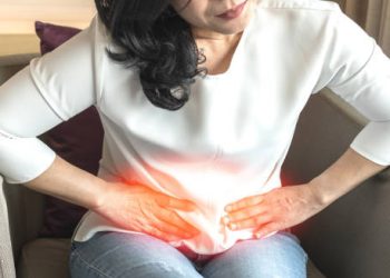 Woman holding lower abdomen in pain indicating symptoms of kidney stones