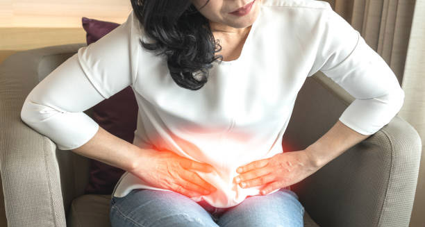 Woman holding lower abdomen in pain indicating symptoms of kidney stones